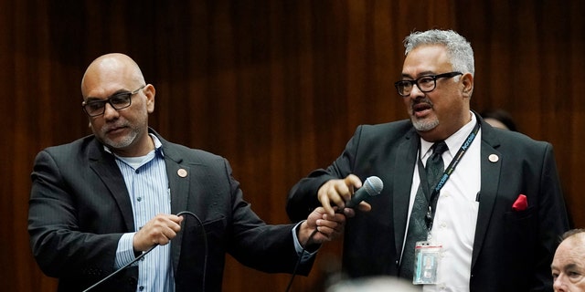 Rep. Lorenzo Sierra, D-Avondale, right, borrows a microphone from Rep. Diego Espinoza, D-Tolleson, prior to a vote on the Arizona budget at the Arizona Capitol June 24, 2021, in Phoenix. 