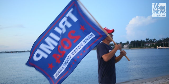A man holds a Trump 2024 flag outside Mar-a-Lago in Palm Beach, Florida, following the FBI raid on Donald Trump's home.
