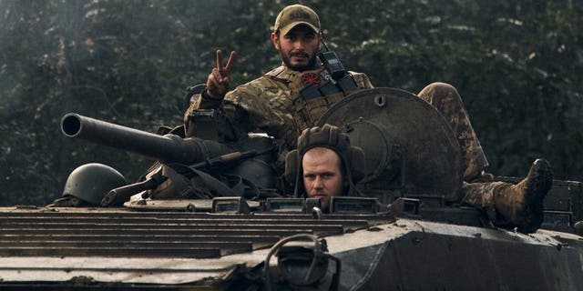 A Ukrainian soldier shows a V-sign atop a vehicle in Izium, Kharkiv region, Ukraine, Tuesday, Sept. 13, 2022.