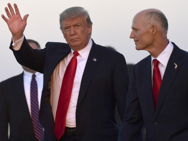 President Donald Trump, left, waves as he walks with Florida Gov. Rick Scott, right, after arriving on Air Force One at Southwest Florida International Airport in Fort Myers, Fla., Wednesday, Oct. 31, 2018. Trump is campaigning for Scott, who is challenging incumbent Democratic Sen. Bill Nelson for a seat in the Senate.