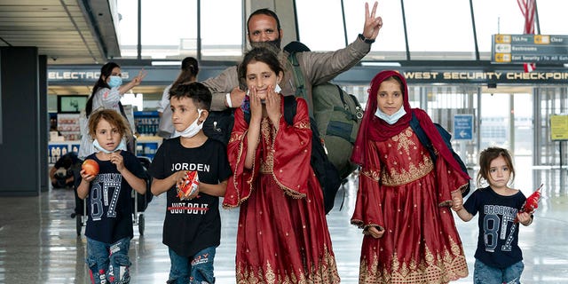 Families evacuated from Kabul, Afghanistan, walk through the terminal after arriving at Washington Dulles International Airport, in Chantilly, Virginia, in 2021.