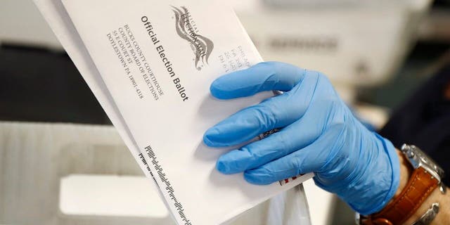 A worker processes mail-in ballots at the Bucks County Board of Elections office prior to the primary election in Doylestown, Pa.