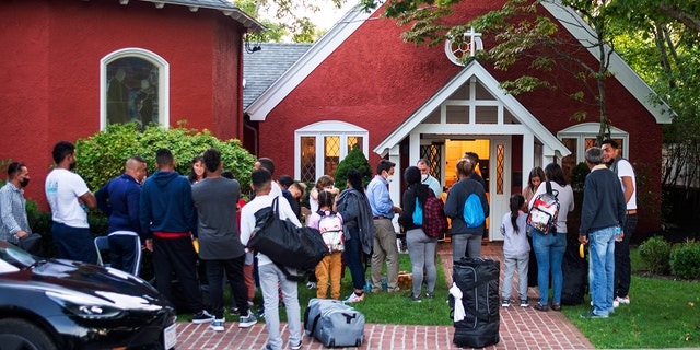 Immigrants gather with their belongings outside St. Andrews Episcopal Church, Wednesday Sept. 14, 2022, in Edgartown, Mass., on Martha's Vineyard. 