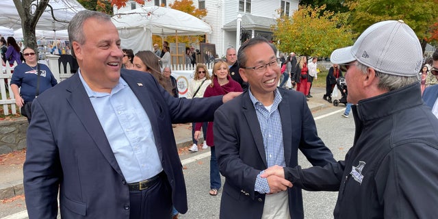 Former Republican Gov. Chris Christie of New Jersey (left) joins GOP nominee Allan Fung in Rhode Island's Second Congressional District (center), greet voters at the Scituate Art Festival, on Oct. 10, 2022 in North Scituate, Rhode Island. 