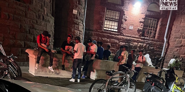 A group of people, said to be newly arrived migrants, congregate outside a packed New York City homeless shelter. 