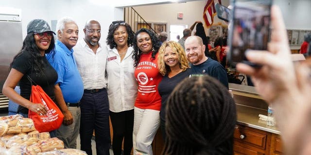 Senator Raphael Warnock (D-GA), center, poses for a photo with supporters as well as U.S. Congresswoman Lucy McBath, second from right, and Georgia Democtratic Lieutenant Governor candidate Charlie Bailey, right, at a Labor Day picnic on September 5, 2022 in Atlanta, Georgia.