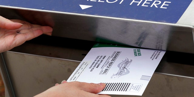 A Michigan voter inserts her absentee voter ballot into a drop box in Troy, Michigan on Oct. 15, 2020.