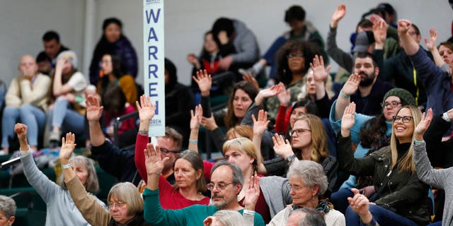 Supporters for Democratic presidential candidate Sen. Elizabeth Warren, D-Mass., raise their hands to be counted during a Democratic Party caucus in Des Moines, Iowa in 2020.