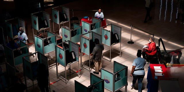 Election workers help as people vote at a polling place June 14, 2022, in Las Vegas.