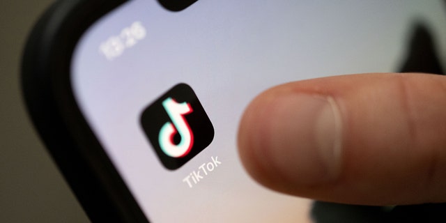 A teenager taps on the TikTok app on a smartphone. 