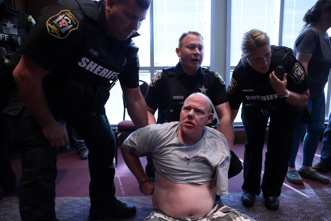 A man is detained by the cops during a Loudoun County School Board meeting