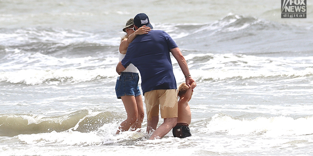 Hunter Biden embraces his wife, Melissa Cohens, as their son Beau plays in the ocean