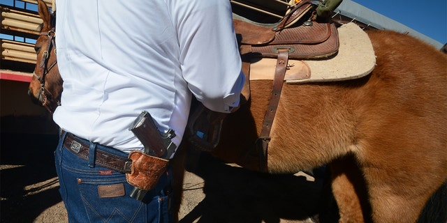 An armed member of a group calling themselves "Cowboys for Trump" prepares to lead a group of other horse-mounted Donald Trump supporters through the downtown streets in Santa Fe, New Mexico, in 2020.