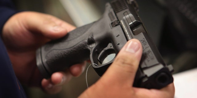 A customer shops for a pistol at a sporting goods store.