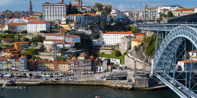 Rabelo port wine barge and The Ponte de Dom Luis I - metal arch bridge over River Douro connecting Porto to V|la Nova de Gaia, Portugal.