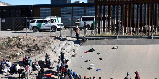 Migrants wait to cross the U.S.-Mexico border from Ciudad Juárez, Mexico, next to U.S. Border Patrol vehicles in El Paso, Texas, Wednesday, Dec. 14, 2022. 