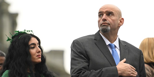 Sen. John Fetterman and his wife, Gisele Barreto Fetterman, stand during the singing of the National Anthem before Josh Shapiro is sworn in as governor of Pennsylvania on Jan. 17, 2023, in Harrisburg.