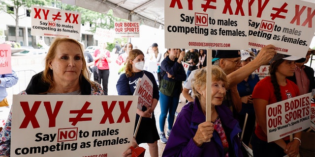 Demonstrators listen to the speaking program during an "Our Bodies, Our Sports" rally for the 50th anniversary of Title IX.