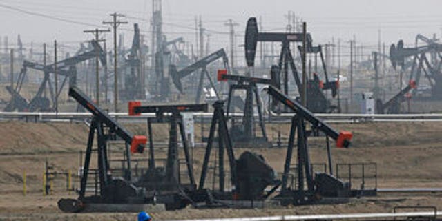 A worker walks past pump jacks operating at the Kern River Oil Field in Bakersfield, California. 