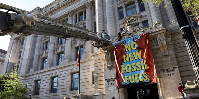 The fire department uses a ladder truck to remove an environmental activists with the group Extinction Rebellion DC after they scaled the Wilson Building as part of an Earth Day rally against fossil fuels on April 22, 2022 in Washington, D.C.