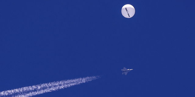 A Chinese spy craft drifts above the Atlantic Ocean, just off the coast of South Carolina, with a fighter jet and its contrail seen below it, on Saturday, Feb. 4.