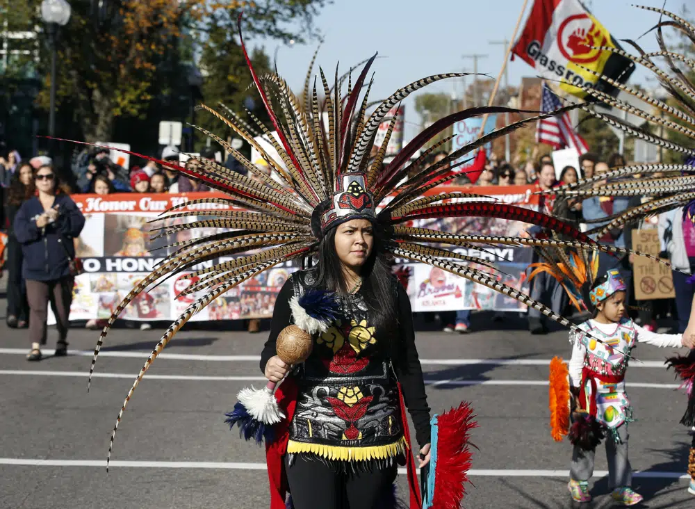 FILE - A woman wearing Native American clothing attends a "No Honor in Racism Rally" march in front of TCF Bank Stadium before an NFL football game between the Minnesota Vikings and the Kansas City Chiefs, Oct. 18, 2015, in Minneapolis. The group objects to the Kansas City Chiefs name, and other teams' use of Native Americans as mascots. As the Kansas City Chiefs return to Super Bowl on Sunday, Feb. 12, 2023, for the first time in two years, the movement to change their name and logo will be there again. (AP Photo/Alex Brandon, File)