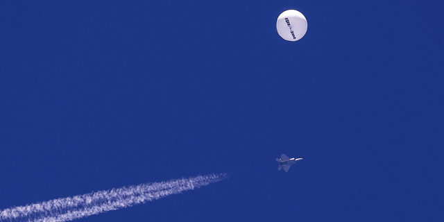 A Chinese spy platform drifts above the Atlantic Ocean, just off the coast of South Carolina, with a fighter jet and its contrail seen below it on Feb. 4.