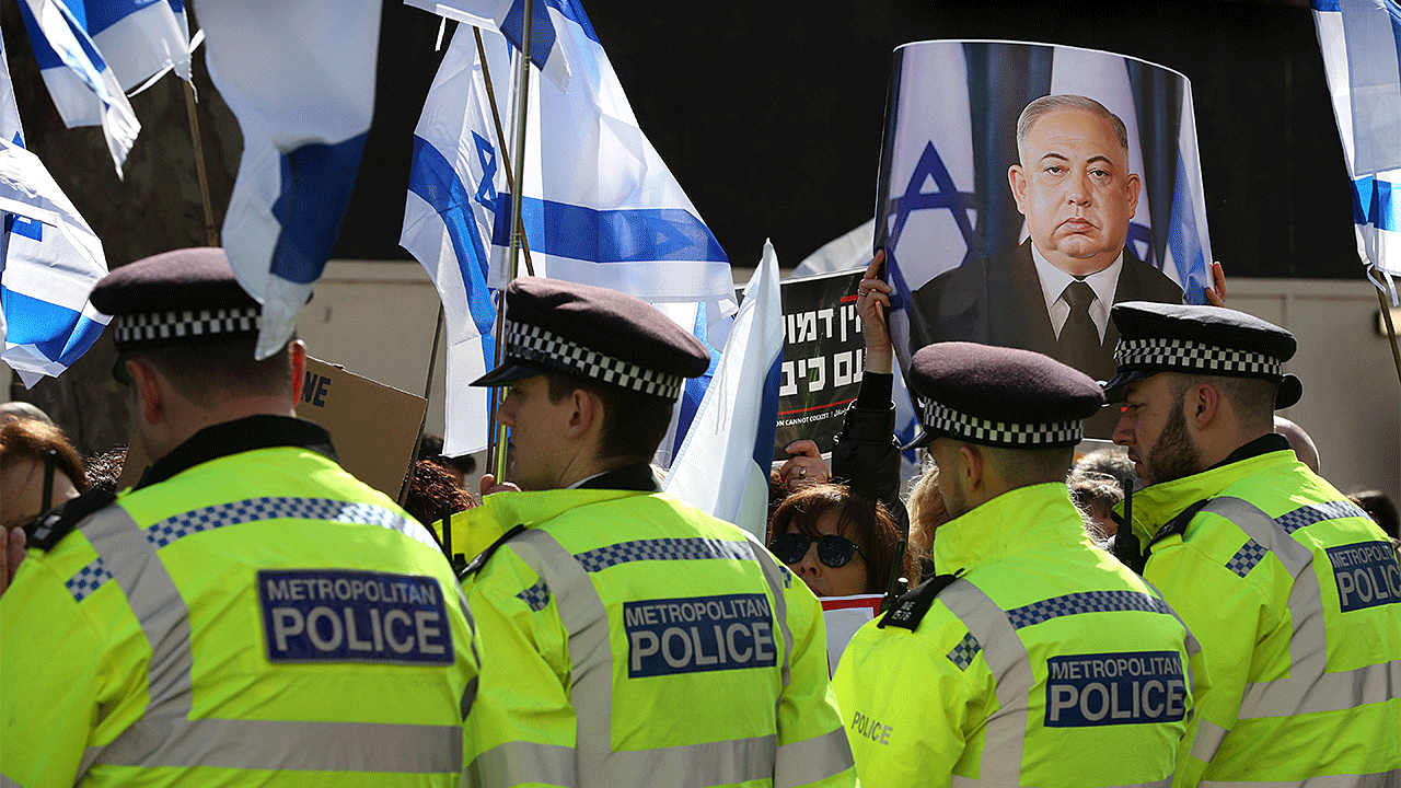 A protester holds a sign making Netanyahu look like a Chinese dictator behind a police cordon at Downing Street on March 24, 2023 in London.