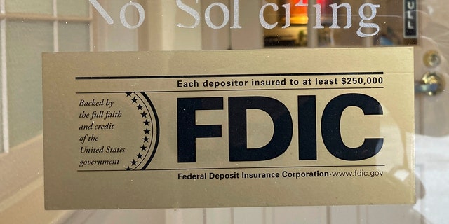 An FDIC sign is posted on a window at a Silicon Valley Bank branch in Wellesley, Mass., on Saturday, March 11, 2023. From winemakers in California to startups across the Atlantic Ocean, companies are scrambling to figure out how to manage their finances after their bank, Silicon Valley Bank, suddenly shut down on Friday. U.S. customers with less than $250,000 in the bank can count on insurance provided by the FDIC.  