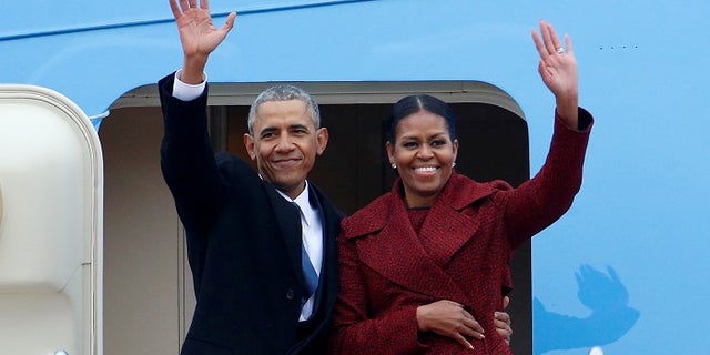 Former President Barack Obama waves with his wife Michelle as they board Special Air Mission 28000, a Boeing 747 which serves as Air Force One, at Joint Base Andrews, Maryland, Jan. 20, 2017.