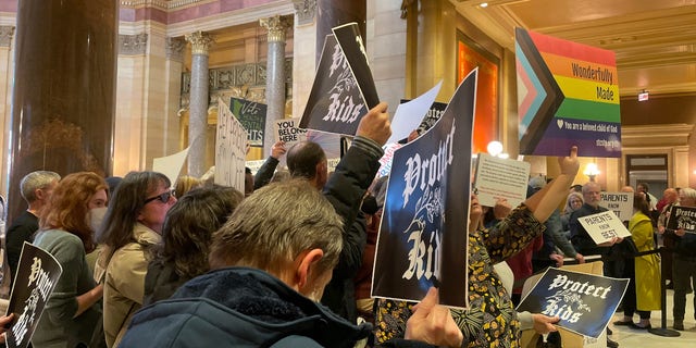 Protesters hold signs as they chant for and against a bill that would make Minnesota a trans refuge state, and strengthen protections for kids and their families who come to the state for gender-affirming care, outside the room where lawmakers would vote on the bill at the state capitol, Thursday, March 23, 2023, in St. Paul, Minnesota.