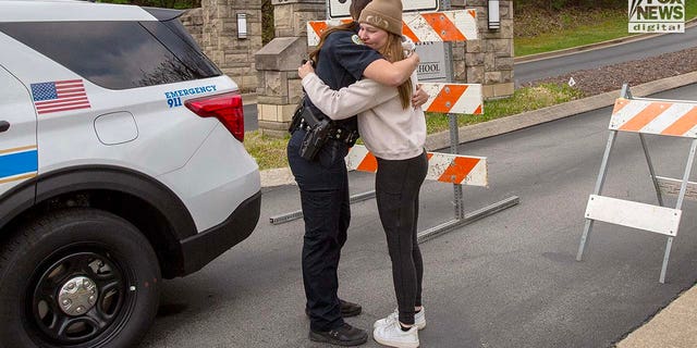 A police officer comforts a mourner outside The Covenant School in Nashville, Tennessee on Tuesday, March 28, 2023. On Monday, six people - three adults and three children - were killed inside the school in a mass shooting.