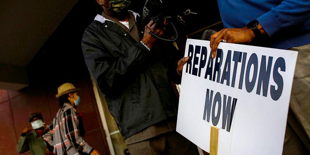 Vernon AME Church pastor Robert Turner holds a reparations now sign after leading a protest from City Hall back to his church in the Greenwood neighborhood on November 18, 2020 in Tulsa, Okla.
