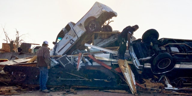 Law-enforcement officers climb through debris on a diner looking for survivors early Saturday, March 25, 2023, in Rolling Fork, Miss.  No one was found. Emergency officials in Mississippi say several people have been killed by tornadoes that tore through the state on Friday night, destroying buildings and knocking out power as severe weather produced hail the size of golf balls moved through several southern states.