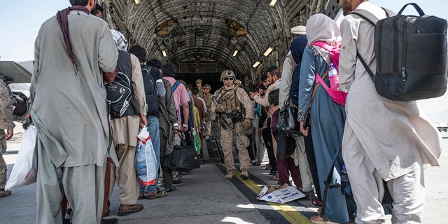 U.S. Airmen and U.S. Marines guide evacuees aboard a U.S. Air Force C-17 Globemaster III in support of the Afghanistan evacuation at Hamid Karzai International Airport in Kabul, Afghanistan, Aug. 21, 2021.