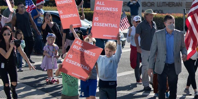 Orange County Supervisor Don Wagner, right, joins a group of protesters