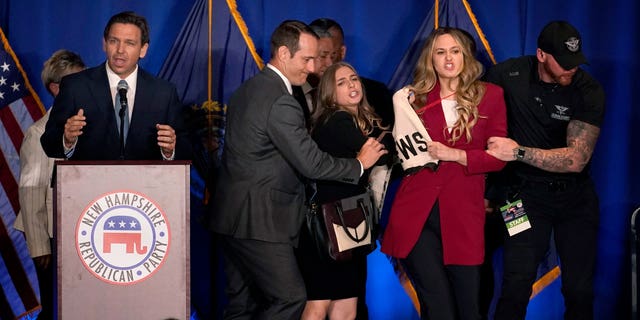 A protester interrupts an address by Florida Gov. Ron DeSantis during a stop at a New Hampshire Republican Party dinner, Friday, April 14, 2023, in Manchester, N.H.