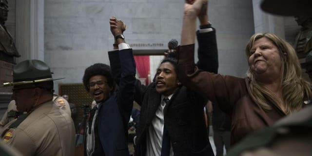 Rep. Justin Pearson, Rep. Justin Jones, Rep. Gloria Johnson People hold their hands up as they exit the House Chamber doors at Tennessee State Capitol Building in Nashville.