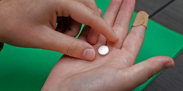 A woman holds the first of two combination pills, mifepristone, which will induce an abortion