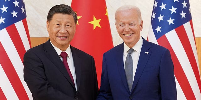 Biden and Xi shake hands in front of the Chinese and US flags