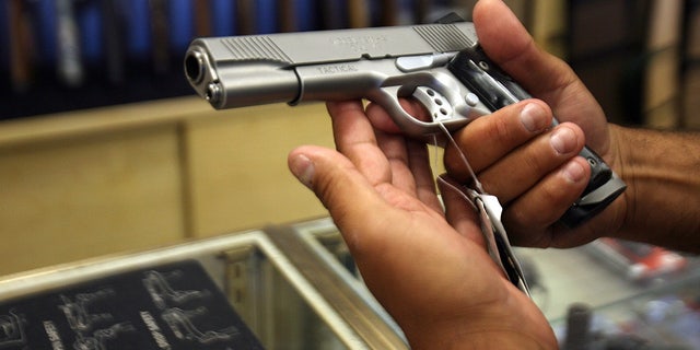 Man holds silver pistol at gun store