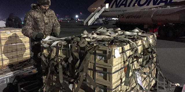 A man in military gear unloads a plane