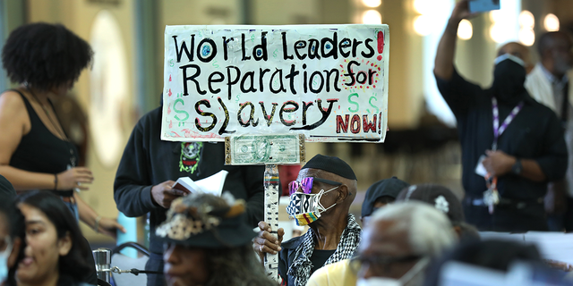 Man holds up sign demanding reparations for slavery