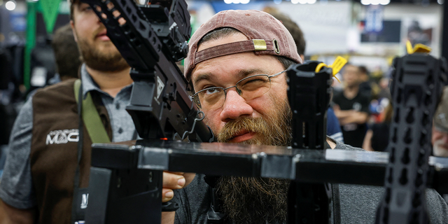 man inspects gun at event