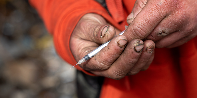 Man in Seattle holding a needle for meth use