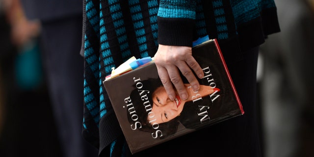 Supreme Court Justice Sonia Sotomayor holds a copy of her book as she visited with students during a celebration to dedicate the new Ralph L. Carr Colorado Judicial Center in Denver, May 2, 2013.