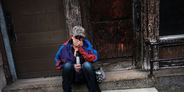 Dora Reynolds, who is unemployed in this picture, sits along a road downtown on Oct. 24, 2016 in East Liverpool, Ohio.