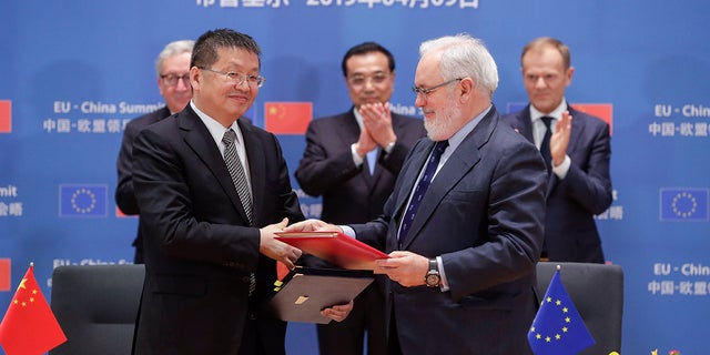 Chinese Minister of Energy Zhang Jianhua and European Climate Commissioner Miguel Arias Canete shake hands at a EU-China summit in Brussels on April 9, 2019.