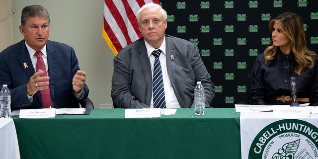 Jim Justice seen at a table between Melania Trump and Joe Manchin