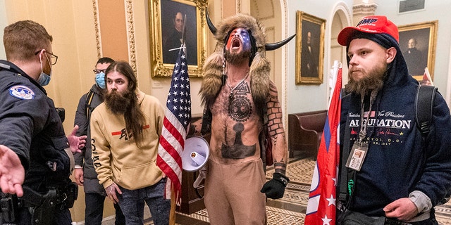 Jacob Chansley stands with Jan. 6 rioters at the U.S. Capitol